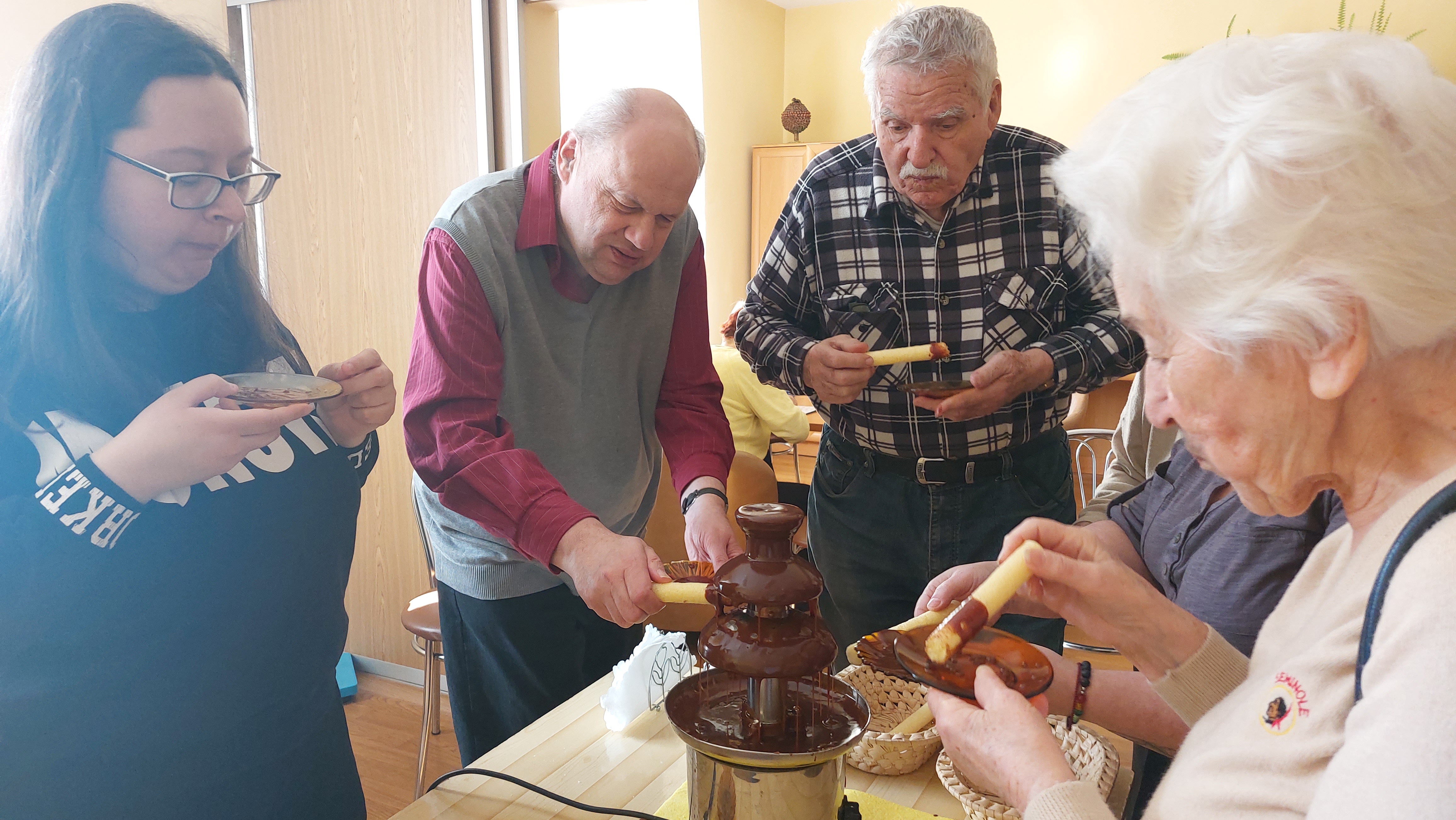 Grupa Seniorów kosztuje czekoladę z fontanny czekoladowej