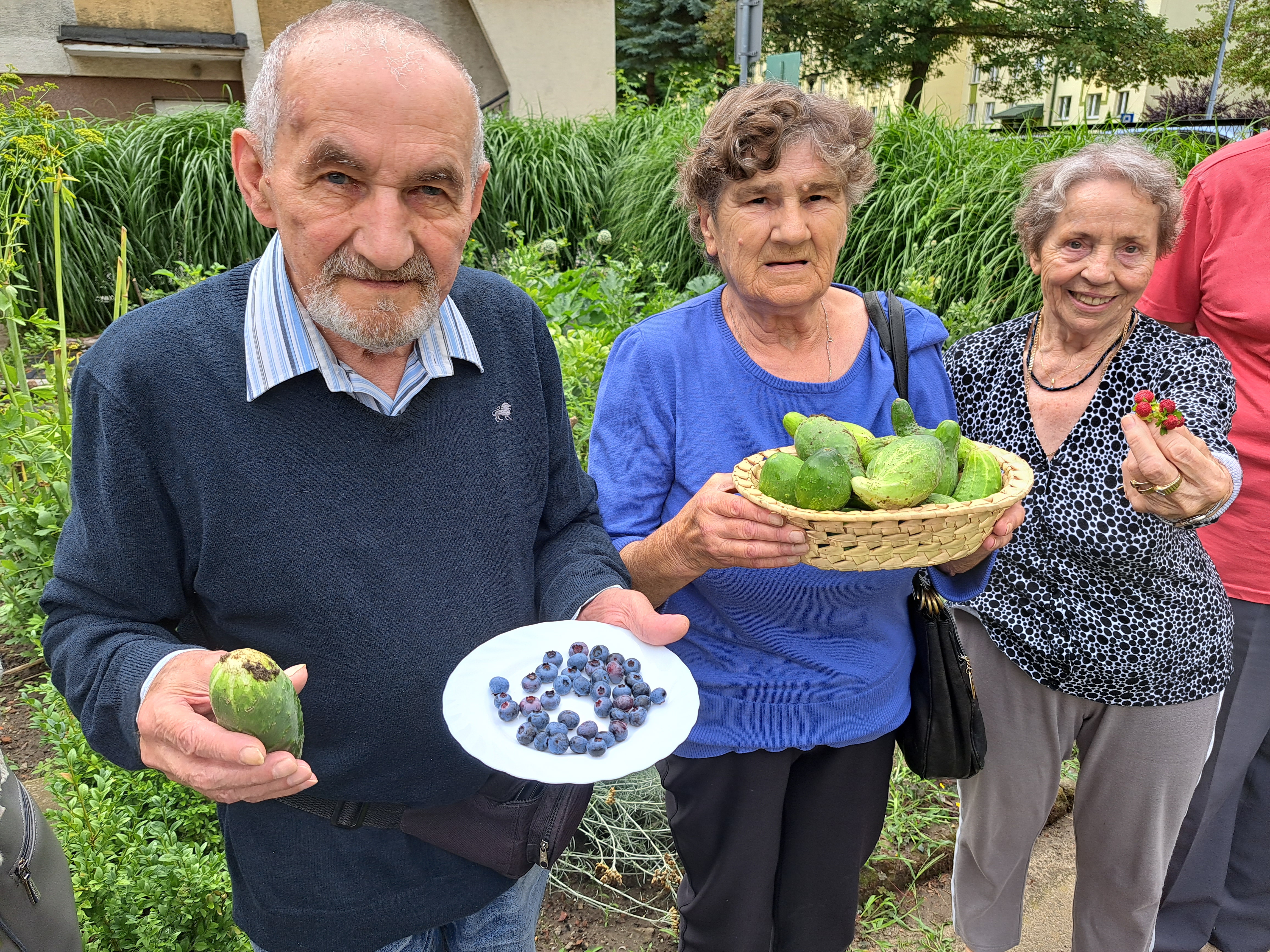 Grupa Seniorów pozuje z zebranymi warzywami i owocami