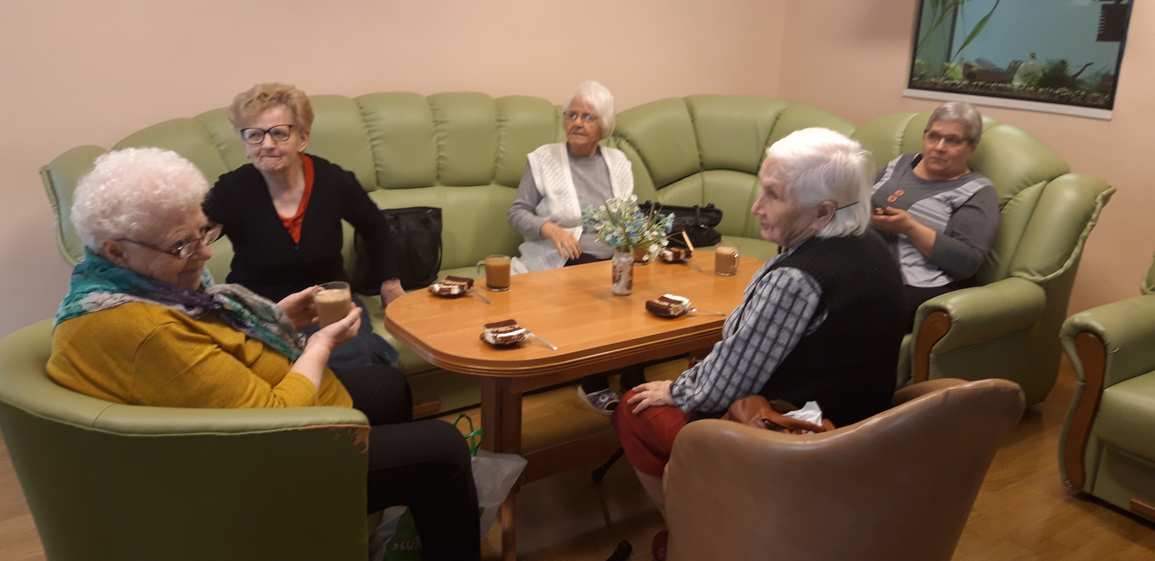 Seniorzy rozmawiają przy kawie i ciastku