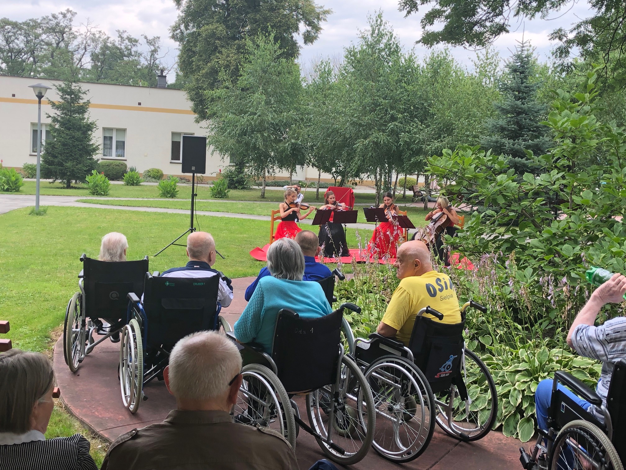 Seniorzy na wózkach inwalidzkich ogladają występ