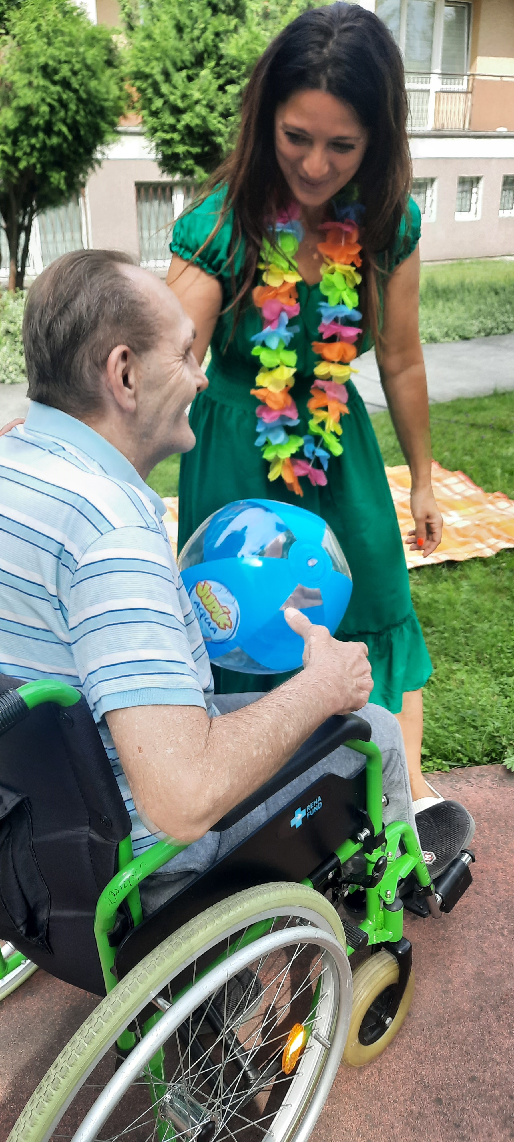 Pracownica DPS uśmiecha się do Seniora siedzącego na wózku