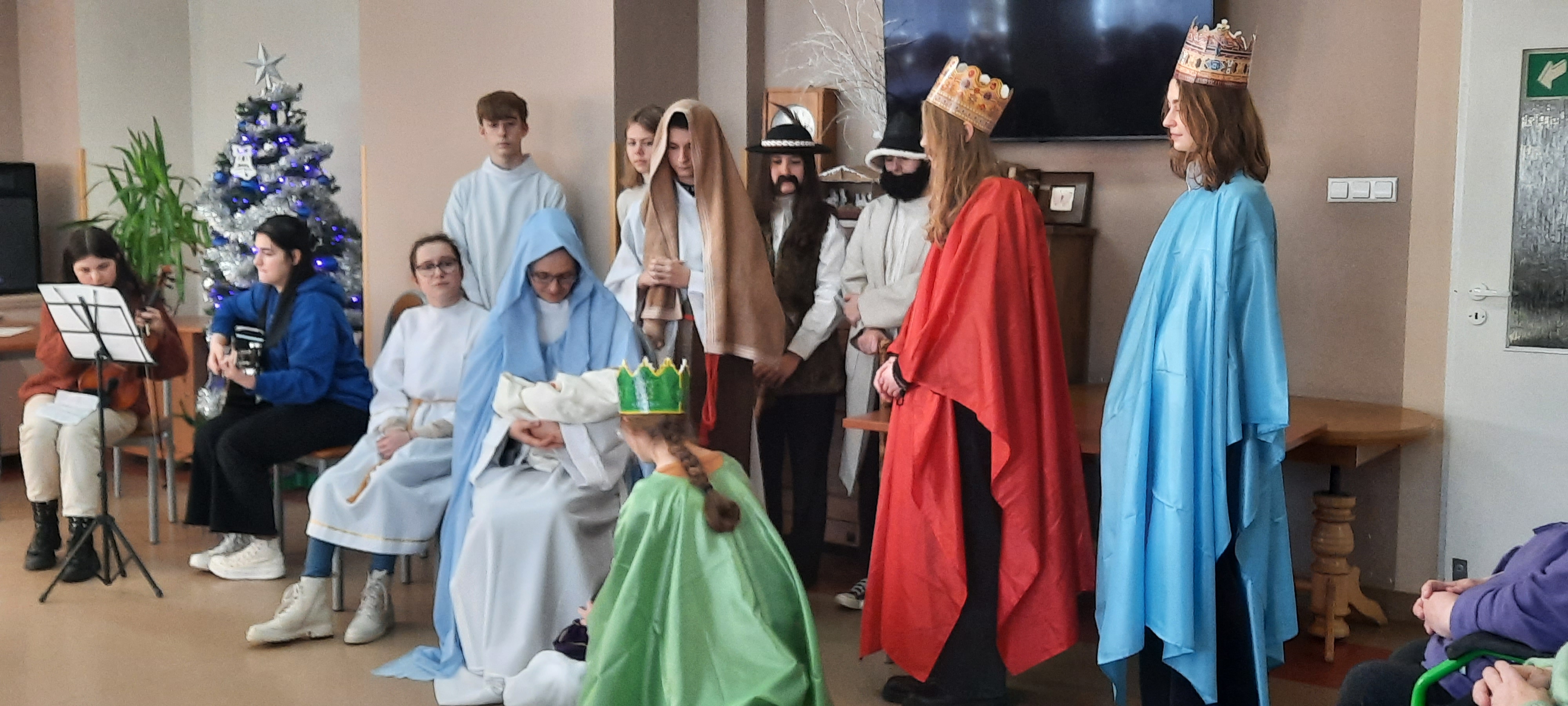 Grupa nastolatków odtwrza scenę ze stajenki betlejemskiej. Na środku Maryja, a wokół niej 3 króli