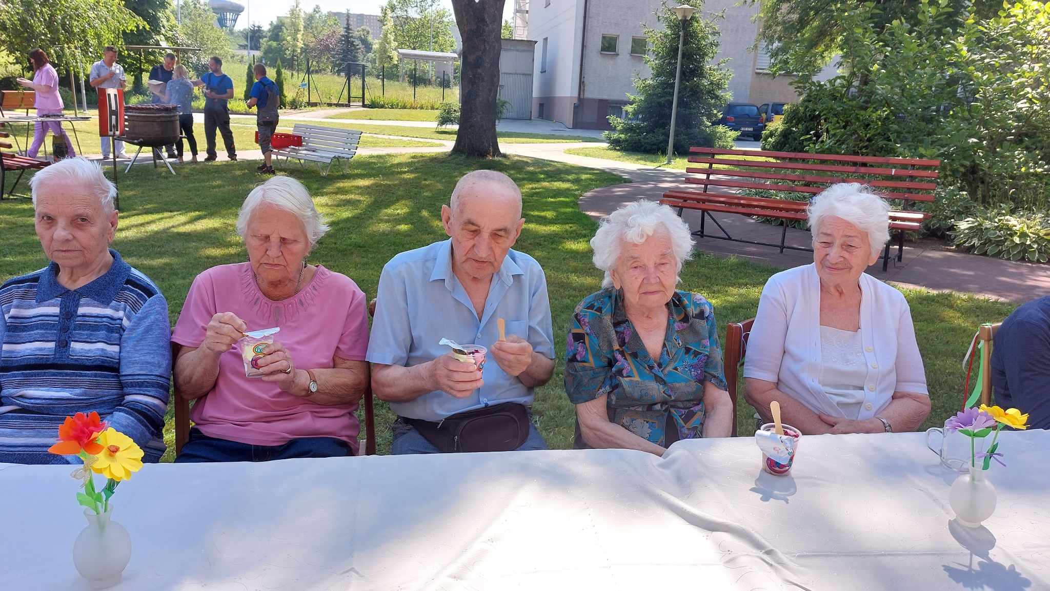 Seniorzy siedzą przy stole i jedzą lody