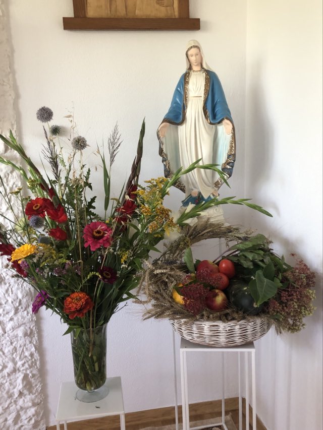 Figura Maryji, przed nią stoją kwiaty oraz owoce w koszyku