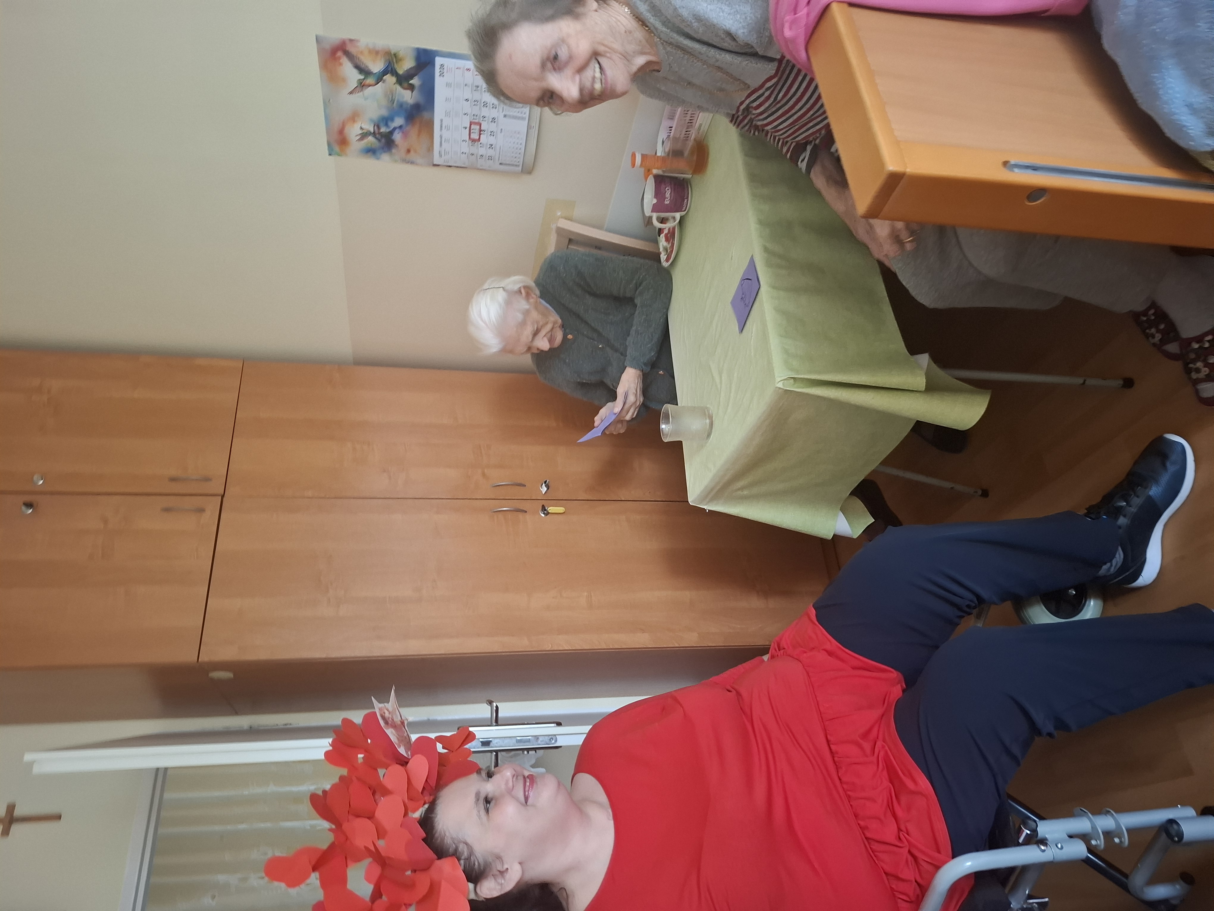 Seniorzy siedzą przy stole, jedzą ciasteczka i piją kawę